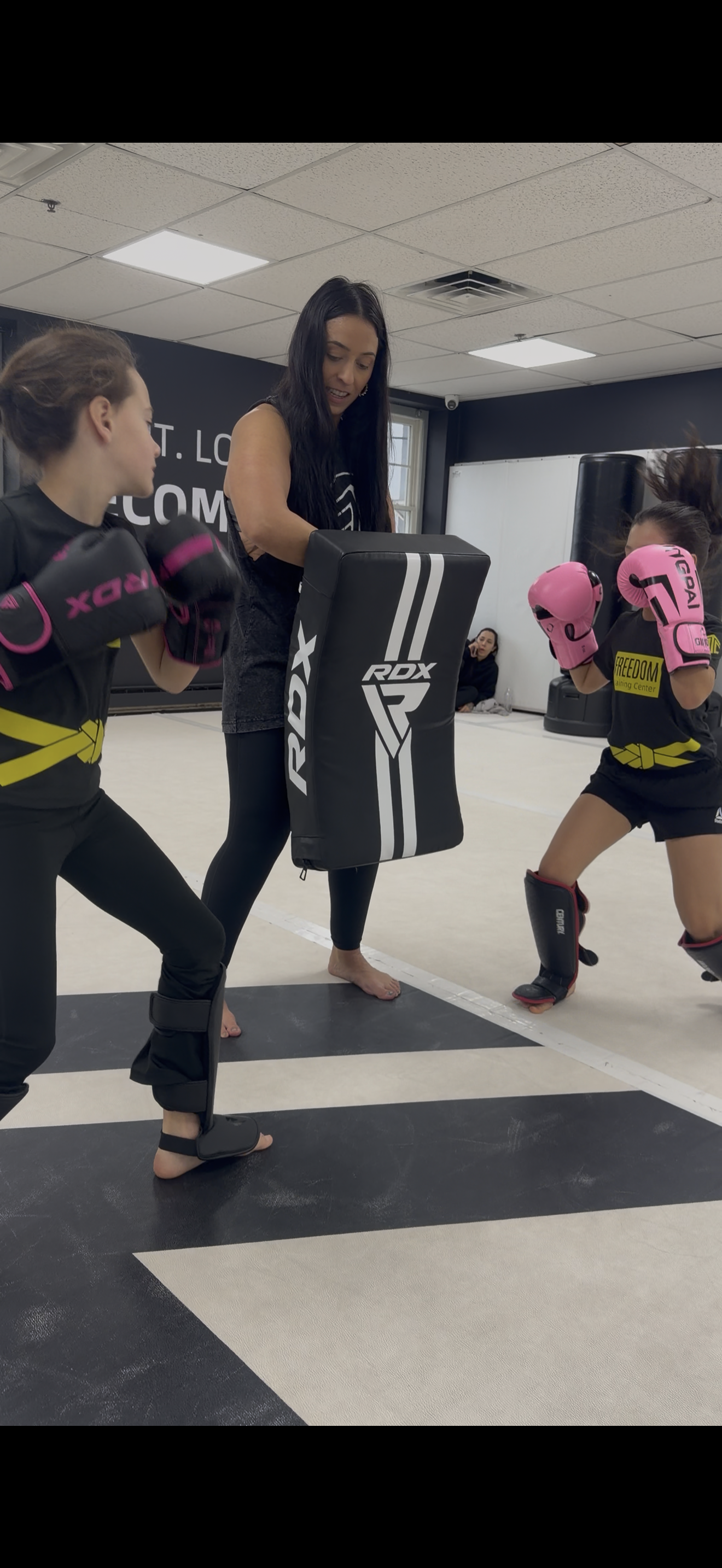 Coach Kaitlin holding pads for kids during Muay Thai class
