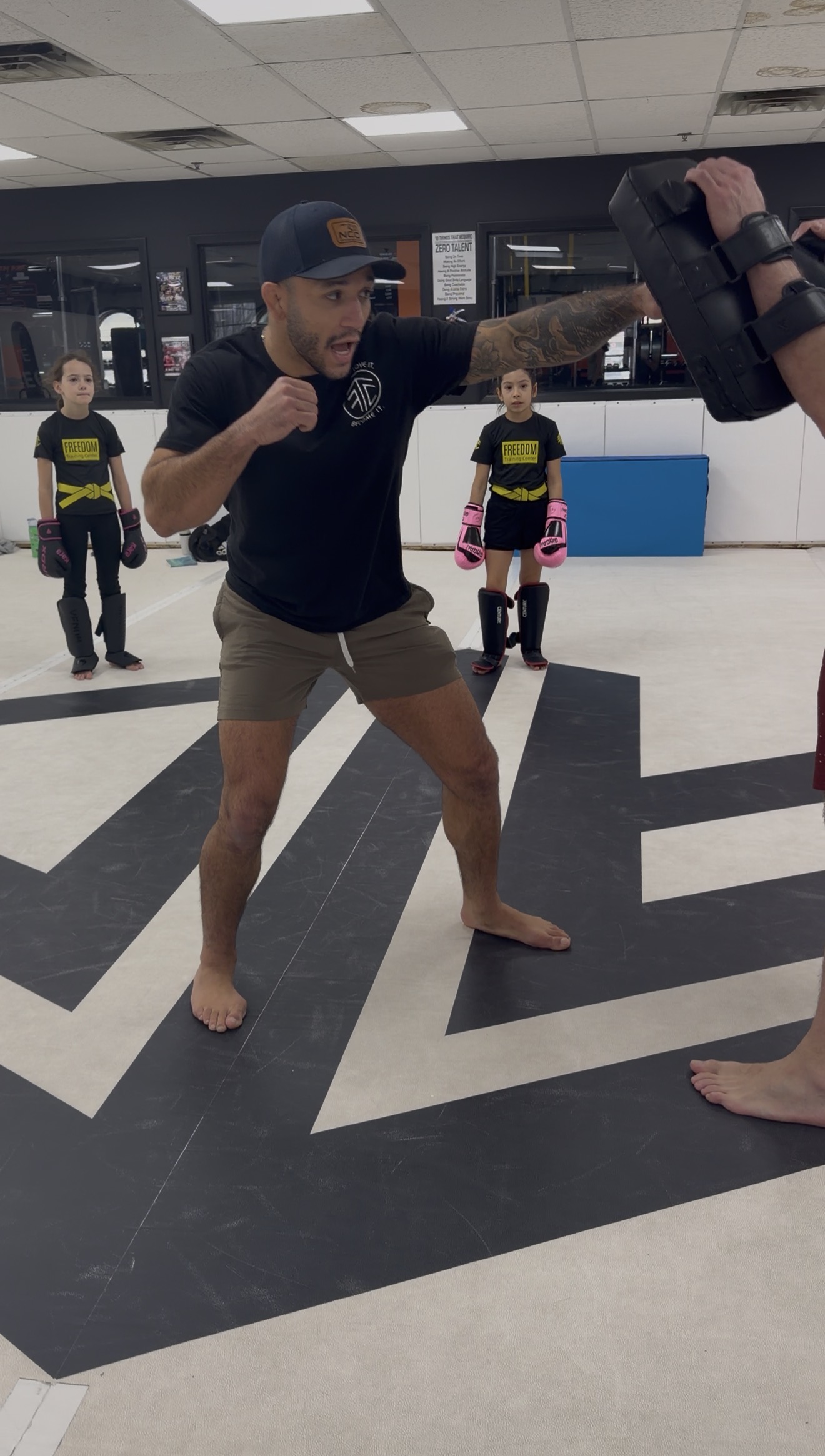 Coach Eric demonstrating Muay Thai technique with kids watching