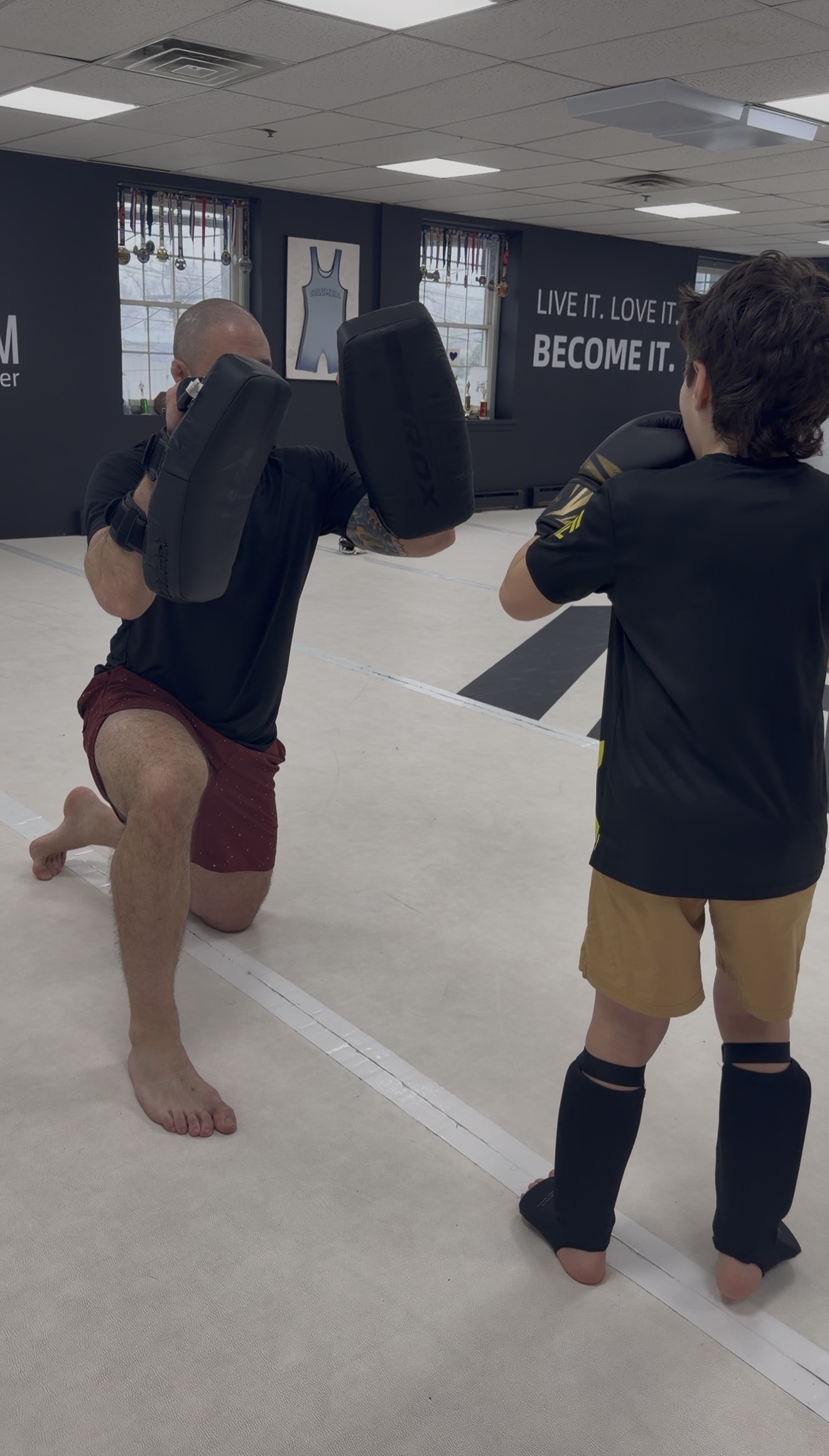Coach Eric holding pads for a kid during a class